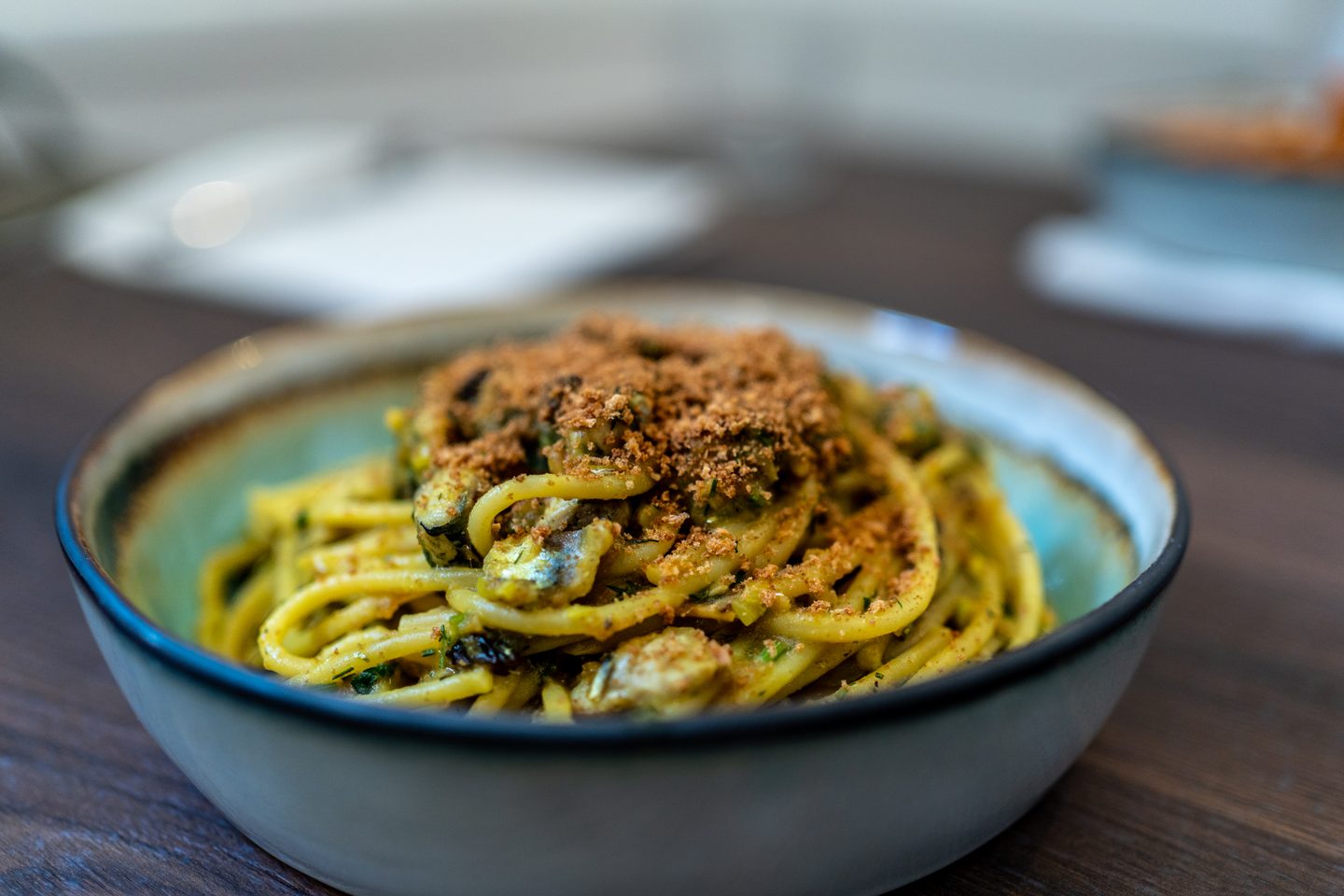 Spaghetti con le sarde, finocchietto e mollica tostata nel piatto azzurro