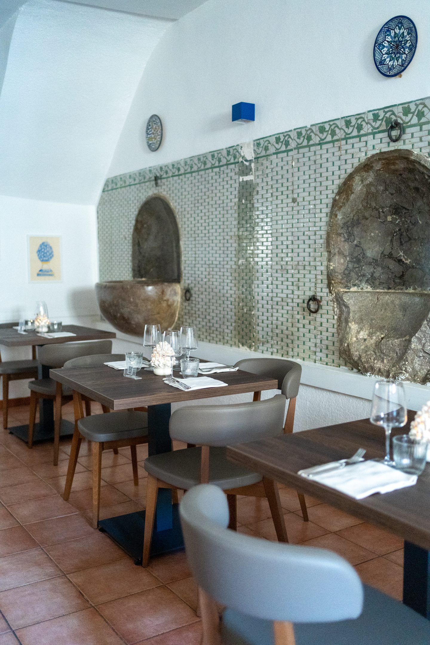 Sala del ristorante con tavoli apparecchiati e poltroncine chiare