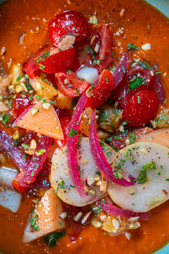 Orto d'estate: verdure, frutta e legumi su crema di pomodoro