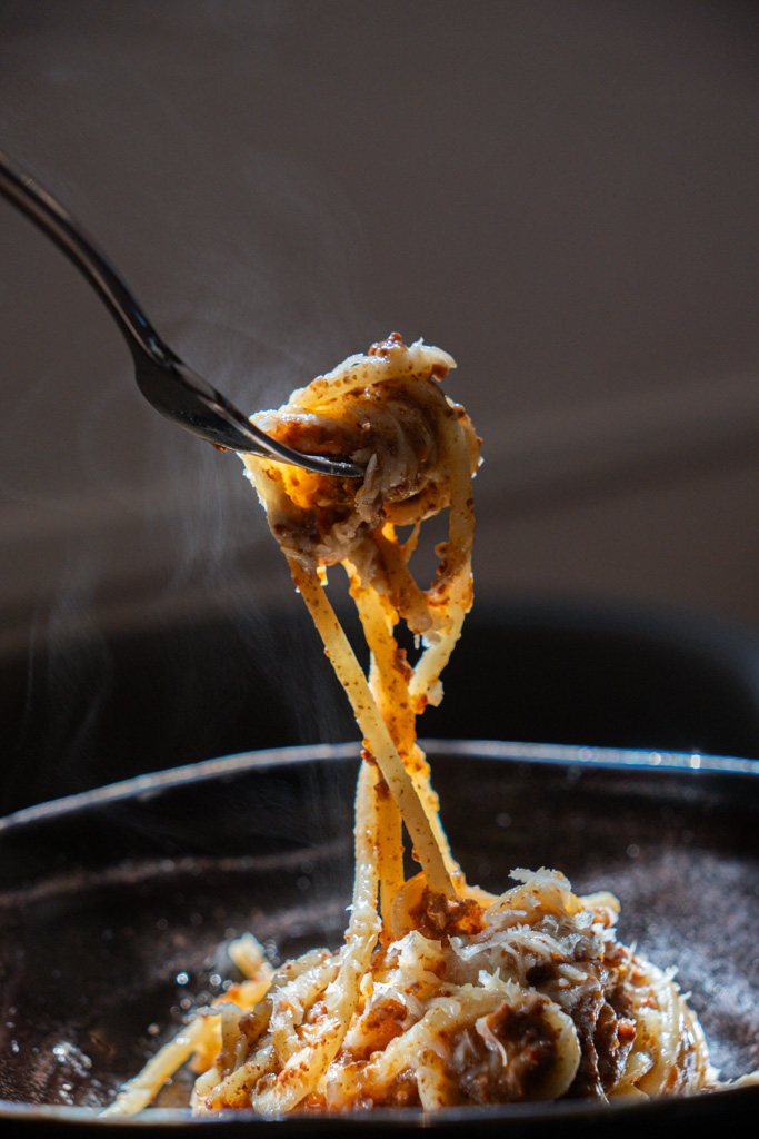 Fusilloni al ragù di maialino nero, fumanti, sollevati con la forchetta
