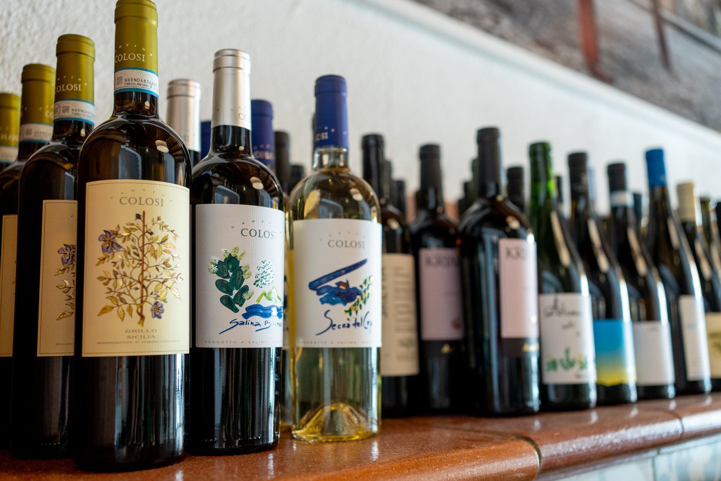 Bottiglie di vino siciliano allineate sulla mensola
